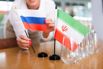 Little flag of Iran on table with bottles of water and flag of Russia put next to it by positive...