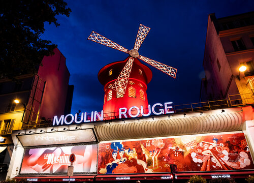 Moulin Rouge, a vintage cabaret with the iconic red mill on top, by night, in Place Blanche, Montmartre district, Paris