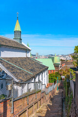 Obraz premium Narrow slope of cobble stairs Kinenzaka going down along the Japanese shikkui plaster walls of the Basilica of the Twenty-Six Holy Martyrs of Japan called Ōura Church in the Nagasaki city of Kyushu.