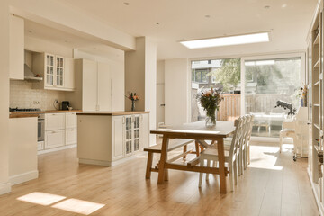 a kitchen and dining area in a house with white cabinets, wood flooring and an open door leading to...
