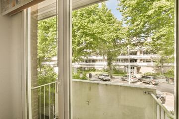 an outside area with trees and buildings in the background, taken from inside a window looking out onto the street
