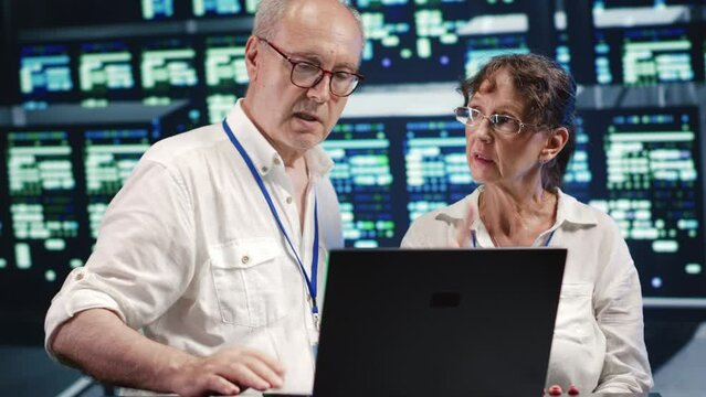 Older colleagues looking around innovative server farm, preparing to start comission on malfunctioning high tech establishment hardware rows in order to ensure perfect operations
