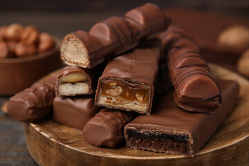 Pieces of different tasty chocolate bars on wooden board, closeup