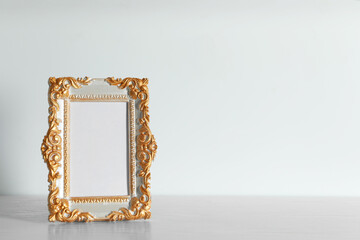 Beautiful golden vintage frame on white wooden table, space for text
