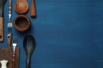 Set of different kitchen utensils on blue wooden table, flat lay. Space for text