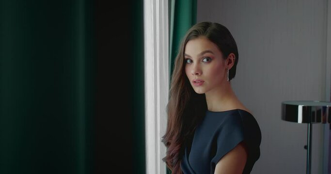 portrait of beautiful young woman near window in new apartment, lady waiting someone, 4K, Prores