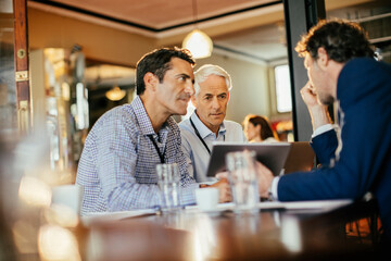 Diverse group of businessmen having a meeting in a cafe and discussing business