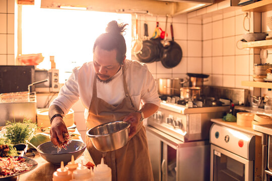 Male asian chef preparing a traditional food dish in a restaurant kitchen