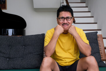 Facial expression of a nervous guy sitting on the sofa watching soccer tournament.