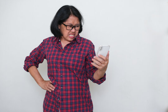 Asian woman expressing her disappointment looking at her smartphone in her left hand