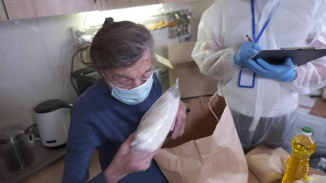 Man with bacteriological protection suit and protective mask delivering food to senior citizens in quarantine during Covid-19 Coronavirus epidemic. Donation box with foods, meals. Quarantine concept.