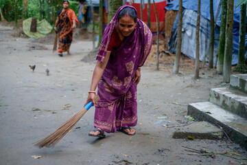 South asian rural housewife cleaning road with a broom, working woman in traditional clothes