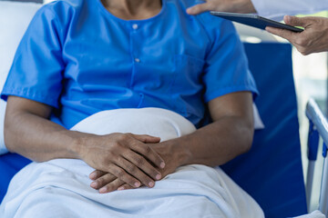 The doctor visits and takes care of the patient on the bed in the room. Two attractive therapists explaining diagnoses in a hospital department treating a man between appointments.