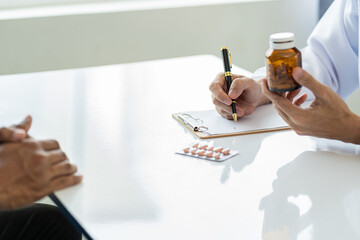 The doctor advises and encourages the patient to sit at the table explaining medications to take in...