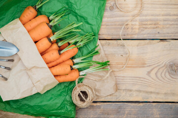 Fresh carrots in a paper bag on a wooden background. Vegetables and root vegetables are useful...