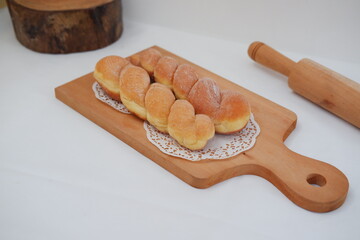 Bread donuts on the wooden table with wooden rolling pin.