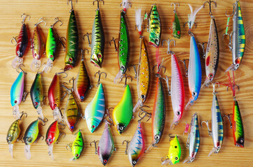 Many spinning lures on a wooden texture.