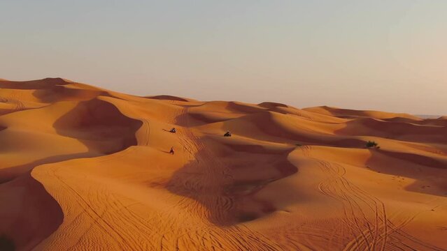 A drone flies over quad bikes driving through the sand dunes of the desert in the United Arab Emirates