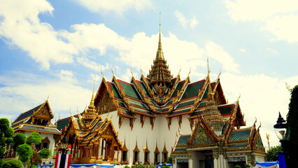 Herrlicher Tempel Wat Phra Kaeo mit vergoldeten Stupas und rotem Dach unter blauem Himmel