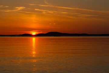 Fototapeta premium Orange Sunset over Tranquil Sea with Reflection