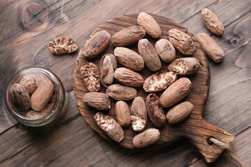 Biji Pala. Nutmeg is the seed or ground spice of several species of the genus Myristica. Myristica fragrans. nutmeg on a brown rustic wooden cutting board. spices. 