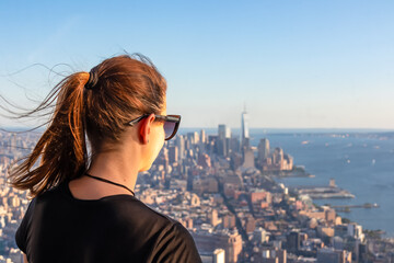 A woman in sunglasses enjoying the view of New York City skyline over the Hudson River during the...