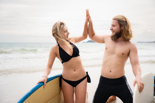Two surfers giving high five on the beach. Two surfers having fun on the beach.