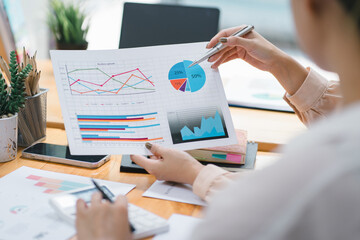 Two businesspeople or an accountant team are analyzing data charts, graphs, and a dashboard on a laptop screen in order to prepare a statistical report and discuss financial data in an office.
