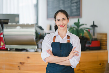 Portrait of a smiling young asian barista waiting for clients at coffee shop.Successful small...