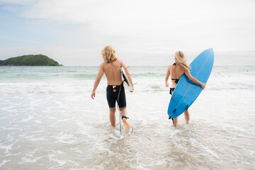 Young man and woman holding surfboards ready to walk into the sea to surf.