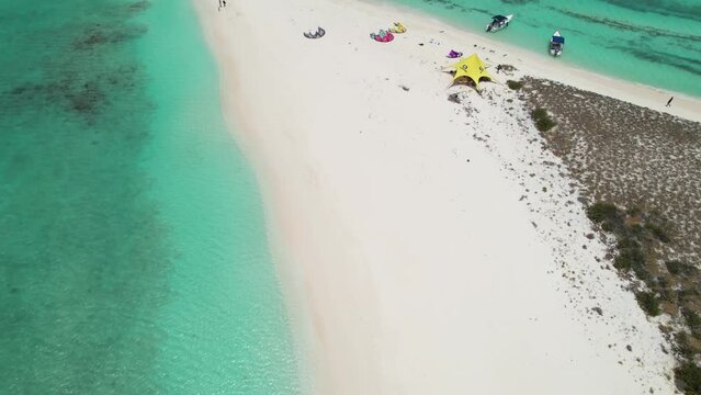 Aerial reveal of kite surfers based at isthmus and island of Cayo De Agua 