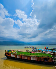 Houseboats stationed at the bank of the Jadukata river in Sunamganj, Bangladesh near the India Bangladesh border with clouds in the sky during the rainy season.