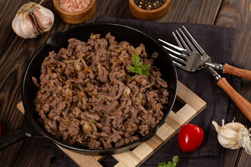 Minced meat fried with onions and spices in a cast-iron frying pan
