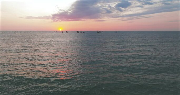 Aerial view of beautiful sunset behind in the ocean fishing boats
