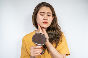 Portrait of Asian woman worry about her face when she saw the problem of acne inflammation occur on her face. 