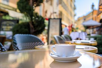 Cup of cappuccino cafe au lait coffee at breakfast on an outdoor table at a bakery cafe in the old...