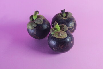 close up of mangosteen fruit on a pink background