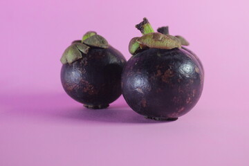 close up of mangosteen fruit on a pink background