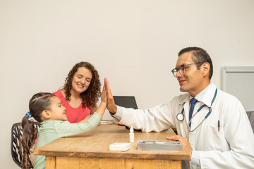 doctor cheering up making high five with a little child girl at doctor's office. single mother...
