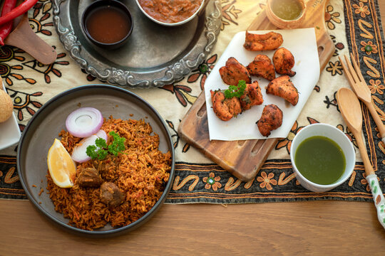 Biryani and Chicken tikka are both popular Indian dishes, ready to eat on the table, top view, natural wooden background