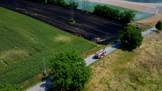 Firefighters Extinguishing Fire Burning Agricultural Field In Summer. Drought Concept. aerial
