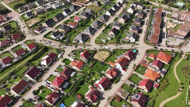Residential area, uniform single family houses with green gardens in a small town, sunny day, drone