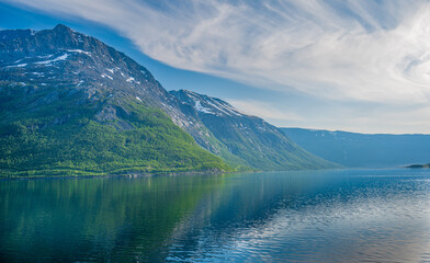 Rocky hill with snow above the fjord