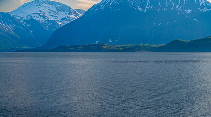 Sea fjord surrounded by rocky mountains with snow