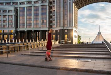Portrait of a mature woman, 59 years old, doing yoga on a city street. Woman doing a headstand.