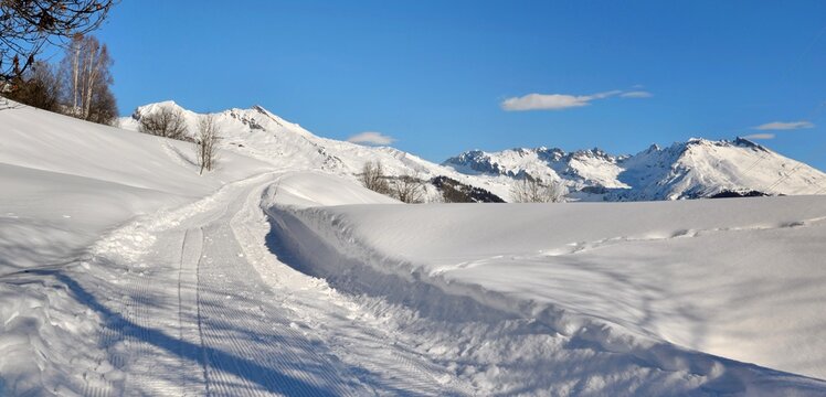 snowy  footpath crossing alpine mountain  under blue sky