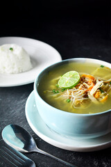 soto ayam, soto ayam or chicken soto is indonesian traditional food served in bowl and rice. top view in dark and texture background. soto ayam kudus.