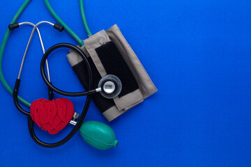Medical Stethoscope with Mercurial Blood Pressure Machine isolated on a blue background with a Red heart. Flat lay, top view.