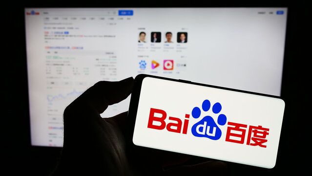 Stuttgart, Germany - 08-15-2023: Person holding mobile phone with logo of Chinese technology company Baidu Inc. on screen in front of business web page. Focus on phone display.