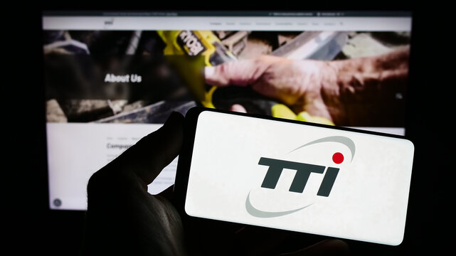 Stuttgart, Germany - 08-15-2023: Person holding smartphone with logo of Techtronic Industries Company Limited (TTI) on screen in front of website. Focus on phone display.